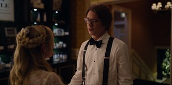 Movie still from “About Fate” (2022), directed by Marius Vaysberg – A man in a bow tie and glasses talking to a woman in a white shirt; Medium shot, Over the shoulder angle
