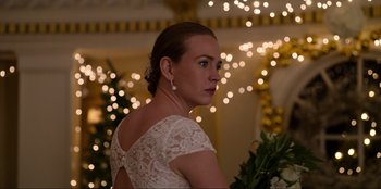 Movie still from “About Fate” (2022), directed by Marius Vaysberg – A woman in a white dress standing in front of christmas lights; Close Up shot, Over the shoulder angle