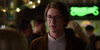 Movie still from “About Fate” (2022), directed by Marius Vaysberg – A young man wearing glasses and a brown jacket; Close Up shot, Over the shoulder angle
