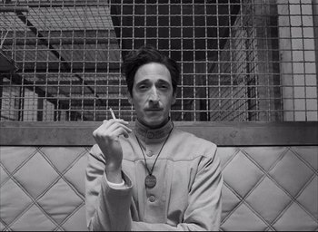 Movie still from “The French Dispatch” (2021), directed by Wes Anderson – A black and white photo of a man smoking a cigarette; Close Up shot, Low angle