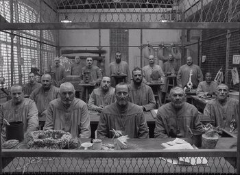 Movie still from “The French Dispatch” (2021), directed by Wes Anderson – A black and white photo of a group of men sitting at a table; Wide shot, High angle