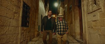 Movie still from “Accident Man: Hitman's Holiday” (2022), directed by George Kirby – Two men walking down a street at night; Wide shot, High angle