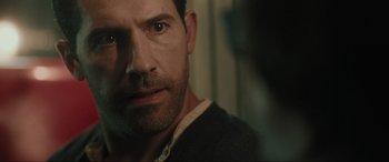 Movie still from “Accident Man: Hitman's Holiday” (2022), directed by George Kirby – A man's face in a dark room; Close Up shot, Over the shoulder angle