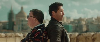 Movie still from “Accident Man: Hitman's Holiday” (2022), directed by George Kirby – Two men standing next to each other in front of a city; Close Up shot, Over the shoulder angle