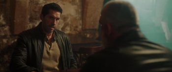 Movie still from “Accident Man: Hitman's Holiday” (2022), directed by George Kirby – A man in a leather jacket talking to another man in a leather jacket; Medium shot, Over the shoulder angle