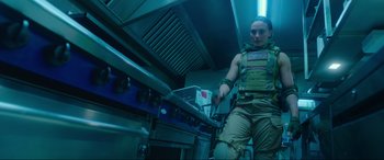 Movie still from “Accident Man: Hitman's Holiday” (2022), directed by George Kirby – A person in a kitchen with a knife in his hand; Medium shot, Low angle