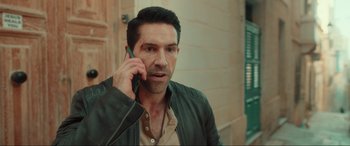 Movie still from “Accident Man: Hitman's Holiday” (2022), directed by George Kirby – A person talking on a cell phone; Close Up shot, High angle