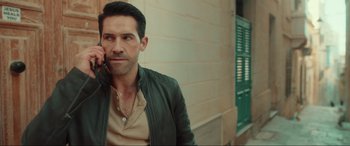 Movie still from “Accident Man: Hitman's Holiday” (2022), directed by George Kirby – A person with a cell phone; Close Up shot, Over the shoulder angle