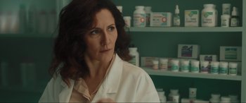 Movie still from “Accident Man: Hitman's Holiday” (2022), directed by George Kirby – A woman in a white lab coat in front of shelves of pills; Close Up shot, Low angle