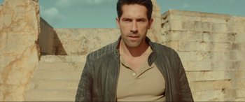 Movie still from “Accident Man: Hitman's Holiday” (2022), directed by George Kirby – A person wearing a leather jacket; Medium shot, Over the shoulder angle