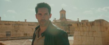 Movie still from “Accident Man: Hitman's Holiday” (2022), directed by George Kirby – A person wearing a leather jacket; Medium shot, Over the shoulder angle