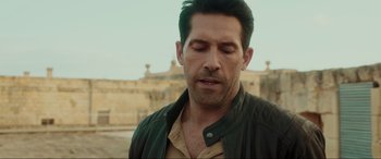 Movie still from “Accident Man: Hitman's Holiday” (2022), directed by George Kirby – A person with his eyes closed; Close Up shot, Over the shoulder angle