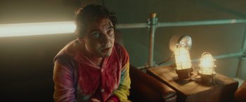 Movie still from “Accident Man: Hitman's Holiday” (2022), directed by George Kirby – A man with a bloody face sitting in a room; Medium shot, Over the shoulder angle