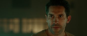 Movie still from “Accident Man: Hitman's Holiday” (2022), directed by George Kirby – A man's face in a dark room; Close Up shot, Over the shoulder angle