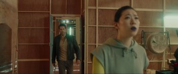 Movie still from “Accident Man: Hitman's Holiday” (2022), directed by George Kirby – A man standing in front of a mirror in a room; Medium shot, Over the shoulder angle