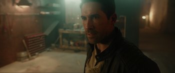 Movie still from “Accident Man: Hitman's Holiday” (2022), directed by George Kirby – A person wearing a jacket in a room; Close Up shot, Over the shoulder angle