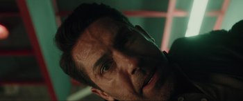 Movie still from “Accident Man: Hitman's Holiday” (2022), directed by George Kirby – A man's face in a dark room; Close Up shot, Overhead angle