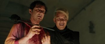 Movie still from “Accident Man: Hitman's Holiday” (2022), directed by George Kirby – Two men are posing for a picture while one is holding a knife; Close Up shot, Low angle