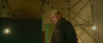 Movie still from “Accident Man: Hitman's Holiday” (2022), directed by George Kirby – A man with blonde hair wearing a leather jacket; Medium shot, Low angle