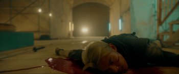 Movie still from “Accident Man: Hitman's Holiday” (2022), directed by George Kirby – A woman laying on the ground in a dark room; Medium shot, High angle