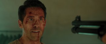 Movie still from “Accident Man: Hitman's Holiday” (2022), directed by George Kirby – A person with blood all over his face; Close Up shot, Over the shoulder angle