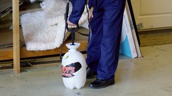 Movie still from “Ace & the Christmas Miracle” (2021), directed by Asif Akbar – A man in blue pants and a blue shirt is holding a white spray bottle; Medium shot, High angle