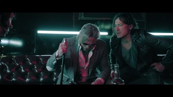 Movie still from “Adverse” (2020), directed by Brian A. Metcalf – Two men sitting at a table in front of drinks; Medium shot, Low angle