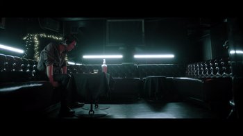 Movie still from “Adverse” (2020), directed by Brian A. Metcalf – A man sitting at a table in a dark room; Wide shot, Low angle