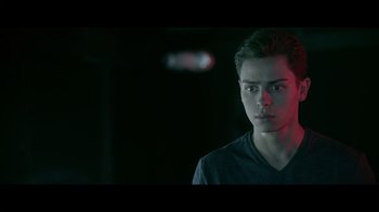Movie still from “Adverse” (2020), directed by Brian A. Metcalf – A young man in a black shirt is looking at the camera; Close Up shot, Over the shoulder angle