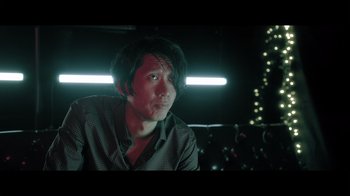 Movie still from “Adverse” (2020), directed by Brian A. Metcalf – A man sitting in front of a bunch of neon lights; Close Up shot, Low angle