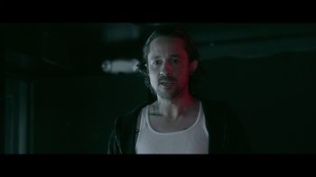 Movie still from “Adverse” (2020), directed by Brian A. Metcalf – A man in a white tank top and a black jacket; Close Up shot, Low angle
