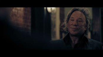 Movie still from “Adverse” (2020), directed by Brian A. Metcalf – A man with long hair is smiling for the camera; Close Up shot, Over the shoulder angle