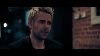 Movie still from “Adverse” (2020), directed by Brian A. Metcalf – A person with blond hair; Close Up shot, Over the shoulder angle