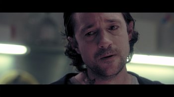 Movie still from “Adverse” (2020), directed by Brian A. Metcalf – A person wearing a shirt; Close Up shot, Over the shoulder angle