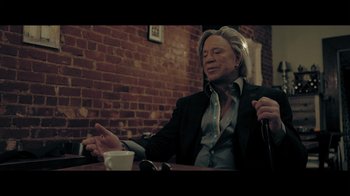 Movie still from “Adverse” (2020), directed by Brian A. Metcalf – A man sitting at a table with a cup of coffee; Medium shot, Low angle