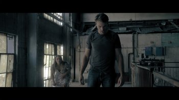 Movie still from “Adverse” (2020), directed by Brian A. Metcalf – A man and a woman are walking in an industrial setting; Medium shot, Low angle