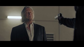 Movie still from “Adverse” (2020), directed by Brian A. Metcalf – A man in a suit is holding a gun in his hand; Close Up shot, Low angle