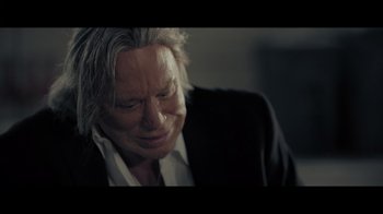 Movie still from “Adverse” (2020), directed by Brian A. Metcalf – An older man in a black suit is crying; Close Up shot, Over the shoulder angle