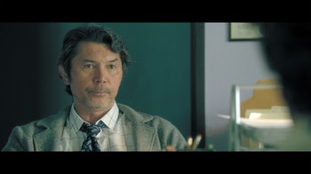 Movie still from “Adverse” (2020), directed by Brian A. Metcalf – A person wearing a suit and tie; Close Up shot, Over the shoulder angle