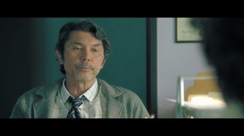 Movie still from “Adverse” (2020), directed by Brian A. Metcalf – A person wearing a suit and tie; Close Up shot, Over the shoulder angle