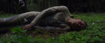 Movie still from “After Earth” (2013), directed by M. Night Shyamalan – A woman laying on the ground in the woods; Medium shot, Low angle