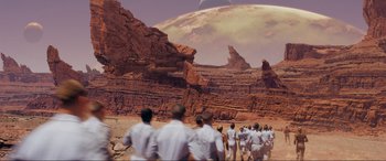 Movie still from “After Earth” (2013), directed by M. Night Shyamalan – A group of people in white clothes walking on a dirt road; Extreme Wide shot, High angle