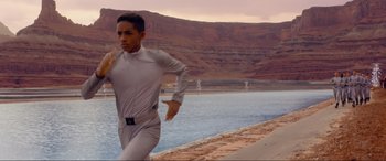 Movie still from “After Earth” (2013), directed by M. Night Shyamalan – A man running on a beach near a body of water; Medium shot, Over the shoulder angle