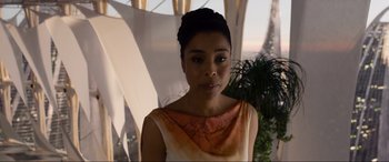 Movie still from “After Earth” (2013), directed by M. Night Shyamalan – A woman in a dress is standing in front of a plant; Close Up shot, Over the shoulder angle