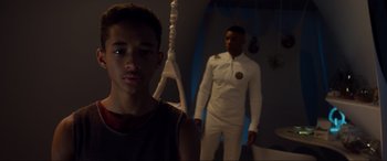 Movie still from “After Earth” (2013), directed by M. Night Shyamalan – A man and a boy standing next to each other in a room; Medium shot, Over the shoulder angle