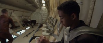 Movie still from “After Earth” (2013), directed by M. Night Shyamalan – A young man sitting in a room eating food; Medium shot, High angle