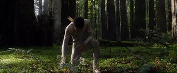 Movie still from “After Earth” (2013), directed by M. Night Shyamalan – A man in the woods is squatting down; Wide shot, Low angle
