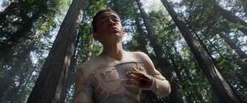 Movie still from “After Earth” (2013), directed by M. Night Shyamalan – A man in a body suit standing in the woods; Medium shot, High angle