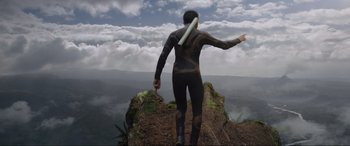 Movie still from “After Earth” (2013), directed by M. Night Shyamalan – A man standing on top of a mountain holding a surfboard; Wide shot, Low angle