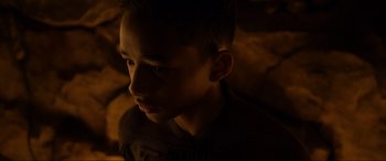 Movie still from “After Earth” (2013), directed by M. Night Shyamalan – A young boy is sitting in the dark looking at the camera; Close Up shot, High angle